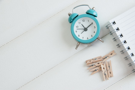 Notebook and alarm clock on white wooden backgroundの写真素材