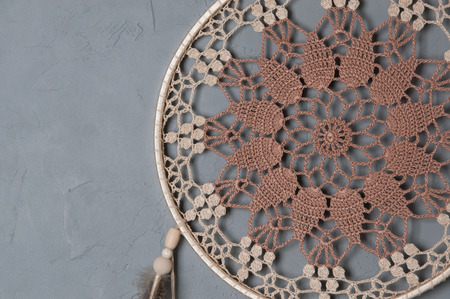 Beige broun crochet doily dream catcher close up on gray textured background. Copy space for textの写真素材