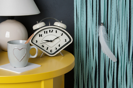 Cup and white table lamp on yellow table in bedroom interior on gray background. Copy space for text.の写真素材