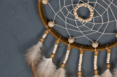 Olive beige dream catcher close up on dark gray textured background. Texture of concrete, copy space for textの写真素材