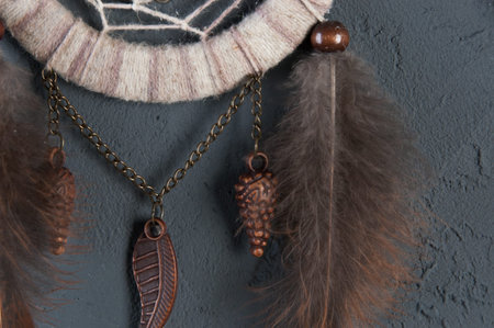 Beige brown dream catcher on dark gray textured background.