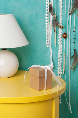 Gift box with bow and lamp in bedroom interior on aquamarine textured background. Bedroom decorの写真素材