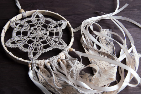 Beige crochet doily dream catcher on brown wooden background.の写真素材