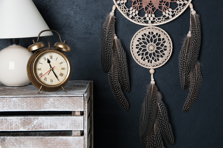 Beige brown dream catcher , alarm clock  and table lamp in bedroom decor on black textured  background.の写真素材