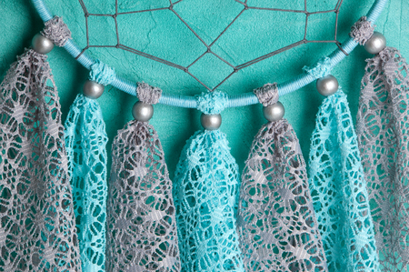 Gray blue lace dream catcher close up on aquamarine textured background.の写真素材