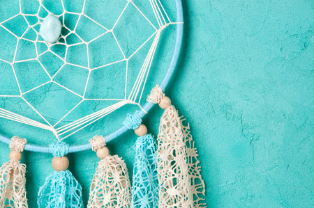 Blue beige dream catcher close up on aquamarine textured background. Copy space for text.の写真素材