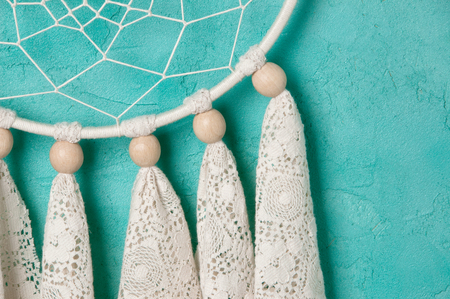 Cream lace dream catcher on aquamarine  textured background. Texture of concrete, copy space for textの写真素材