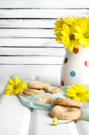 Bouquet of yellow daisies and cookies on wooden white background. Copy space for textの写真素材