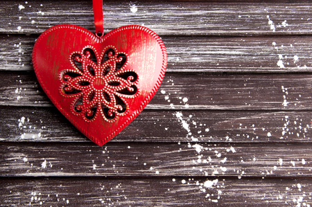 Red Metal Christmas heart on brown shabby wooden background. Christmas decorations, copy space for text.の写真素材