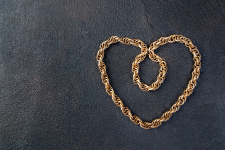Vintage wooden necklace in the shape of a heart on black textured background. Copy space for text.の写真素材