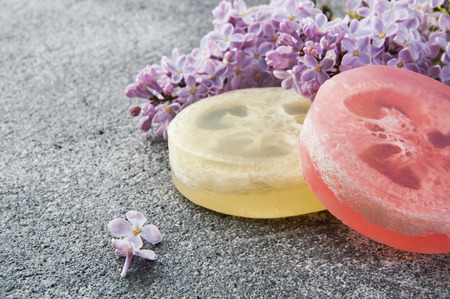 Handmade soap scrub and lilac on gray concrete background. Spa setting and copy space for text.の写真素材