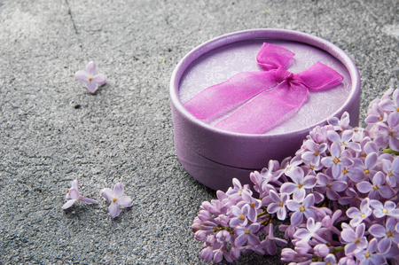 Gift box and bunch of lilac on gray concrete background. Copy space for text.の写真素材