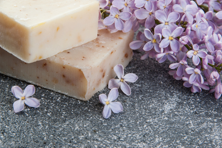 Beige handmade soap scrub and lilac on gray concrete background. Spa setting and copy space for text.の写真素材