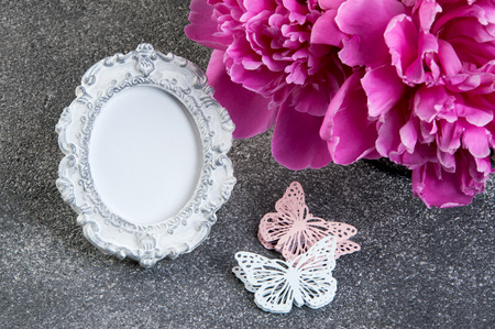 Pink peony, shabby frame and butterflies close up on gray textured background. Texture of concrete and copy space for textの写真素材
