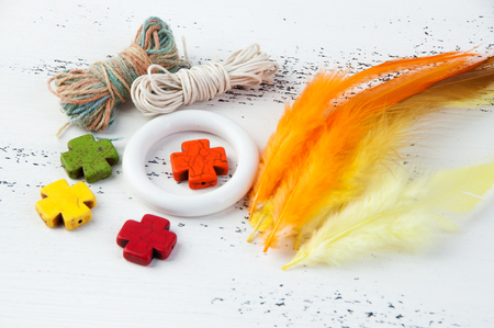 Small white hoop, thread and stone bright crosses to create a dream catcher on a white shabby wooden background. Copy space for text.の写真素材
