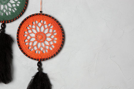 Orange and green small dream catchers on gray textured background. Copy space for text
