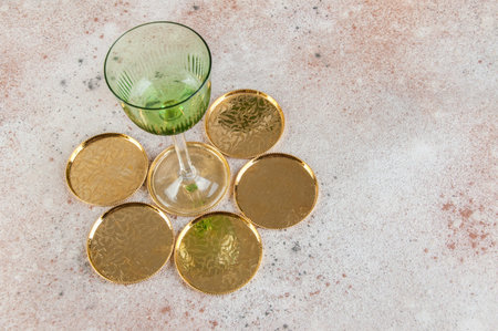 Vintage green wineglass and gold coasters on concrete background. Copy space for text.の写真素材