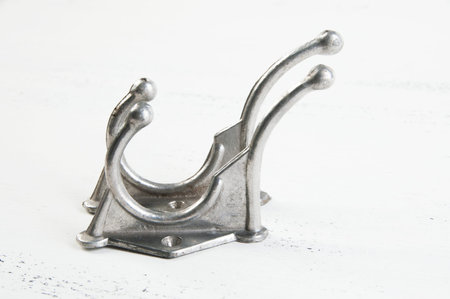 Two vintage metal hooks hangers on shabby white wooden background. Copy space for text.