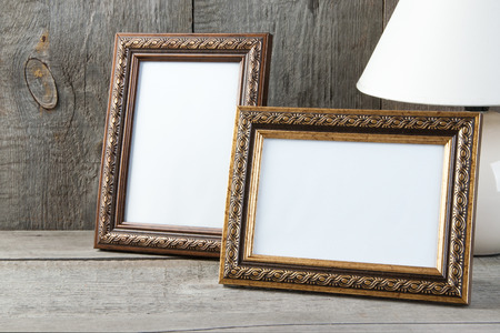 Two empty picture frames and table lamp on old wooden gray textured background. Home decor and copy space for text.の写真素材