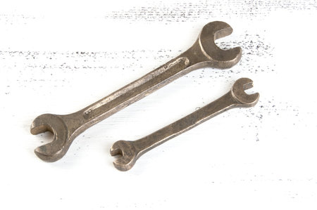 Vintage bronze wrenches on shabby white wooden background. Copy space for text.
