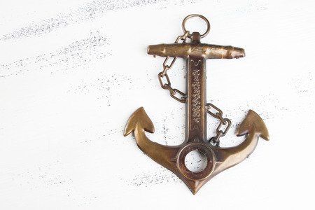Vintage brass anchor on shabby white wooden background. Copy space for text.の写真素材