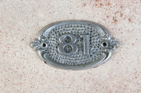 Old aluminum door number on concrete background. Copy space for text.