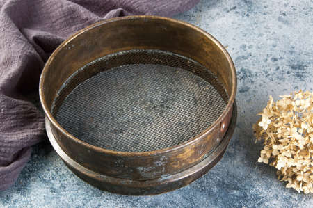 Antique brass  sieve on concrete background. Copy space for text.の写真素材