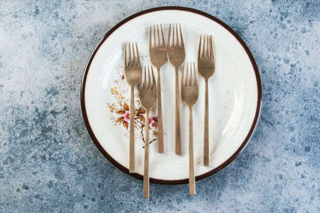 Old bronze forks on vintage dish on concrete background. Copy space for text, food photography props.の写真素材