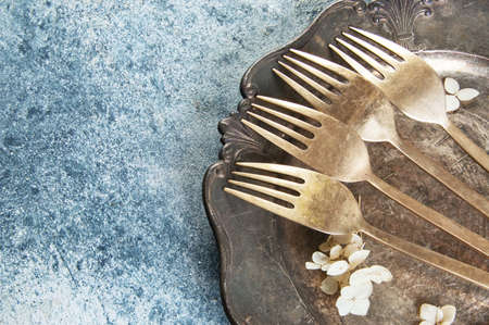 Old bronze forks on vintage dish on concrete background. Copy space for text, food photography props.の写真素材