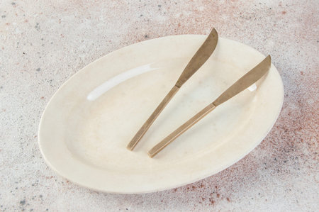 Old bronze knives on vintage oval plate on concrete background. Copy space for text, food...