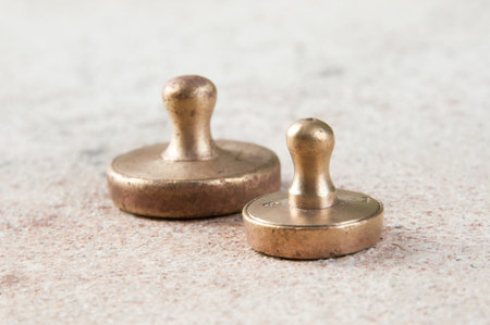 Two antique bronze weights for scales on concrete background. Copy space for text and food photography props.の写真素材