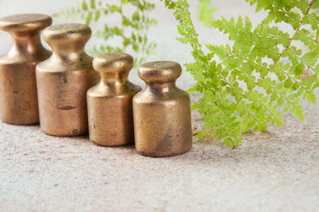 Four antique bronze weights for scales on concrete background. Copy space for text and food photography props.の写真素材