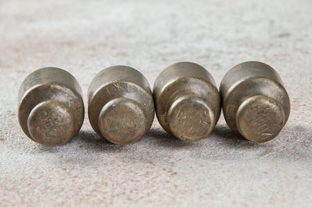 Four antique bronze weights for scales on concrete background. Copy space for text and food...