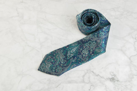 Blue neck tie with pattern on marble background. Copy space for text.