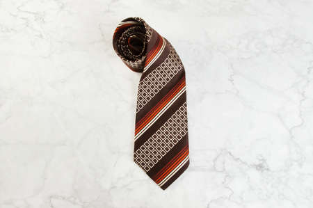 Brown neck tie with geometric pattern on marble background. Copy space for text.の写真素材