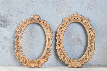 Two antique brass empty picture frames on concrete background. Photography props and copy space for text.の写真素材