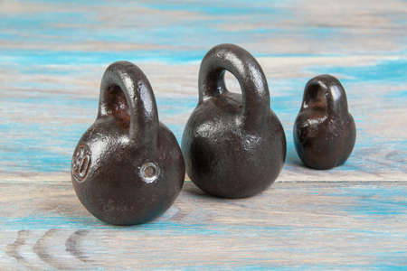 Three antique iron weights for scales on blue wooden background. Copy space for text and food photography props.の写真素材