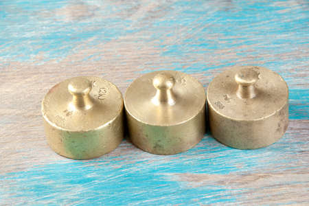 Three antique bronze weights for scales on blue wooden background. Copy space for text and food photography props.の写真素材