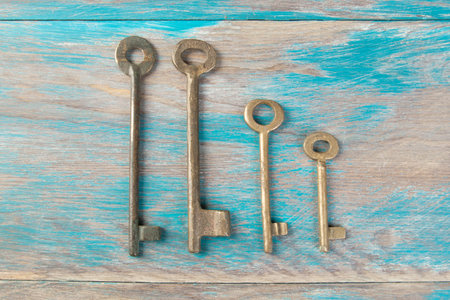 Old brass keys, detail of a classic metal keys on wooden background. Copy space for text