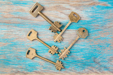 Old brass keys, detail of a classic metal keys on wooden background. Copy space for text