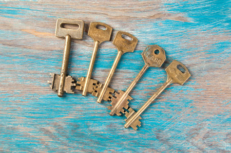 Old brass keys, detail of a classic metal keys on wooden background. Copy space for text