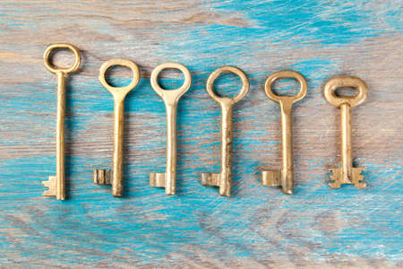 Old brass keys, detail of a classic metal keys on wooden background. Copy space for textの写真素材