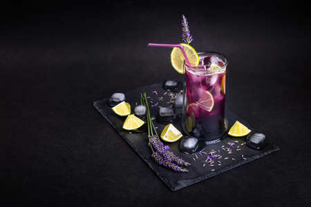 Fresh homemade lemonade with lavender and ice. Delicious purple icy cold party drink on slate board with dark background.の写真素材