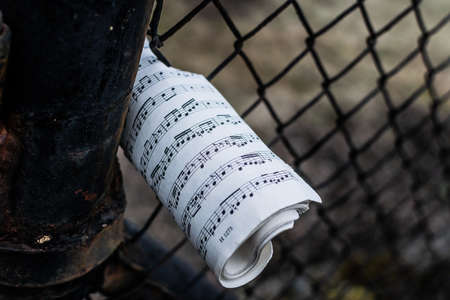 old book of sheet music jammed into a rusty fence on an autumn afternoonの写真素材