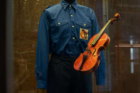 old ancient violin suspended in air next to a blue historic uniformの写真素材
