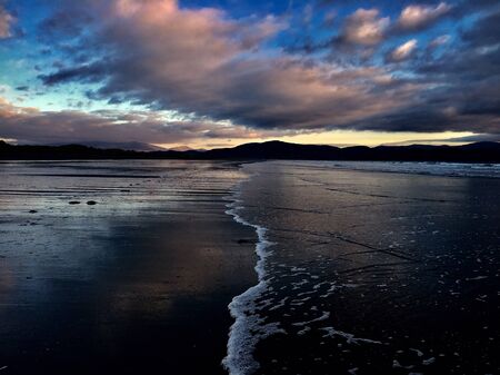 Long beautiful beach with endless wave under big blue clouds in Ireland.の写真素材