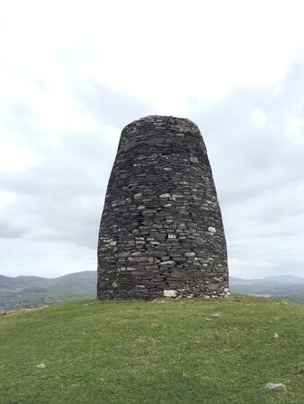 Old round stone defensive tower in Ireland, vertically and with a blue sky with white clouds.の写真素材