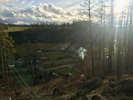 Village in the valley under the forest, lit by sunlight.の写真素材
