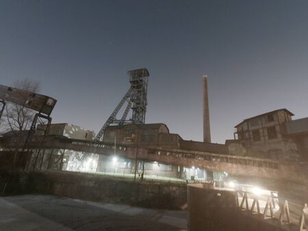 Old closed industrial ironworks at night. Epic metal structures and chimneys lit by the moonの写真素材