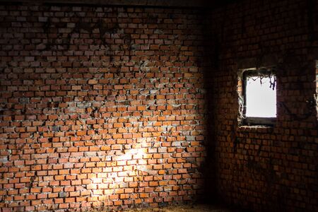 Detail of an ancient red brick wall slightly bleached with salt. Fragments of the narrow white stone windows. The bricks were blocked by metal tie rods. Background use.の写真素材